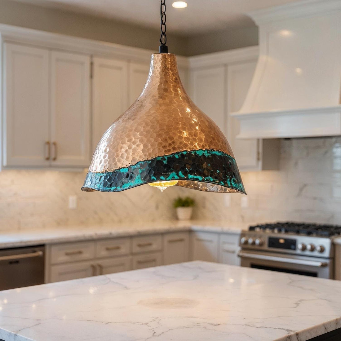 Hammered copper pendant light with green patina edge hanging above a kitchen island