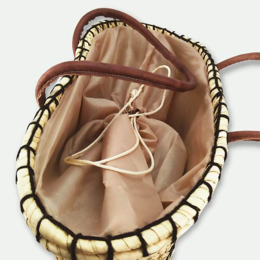 Woven handbag with drawstring closure on a light gray background