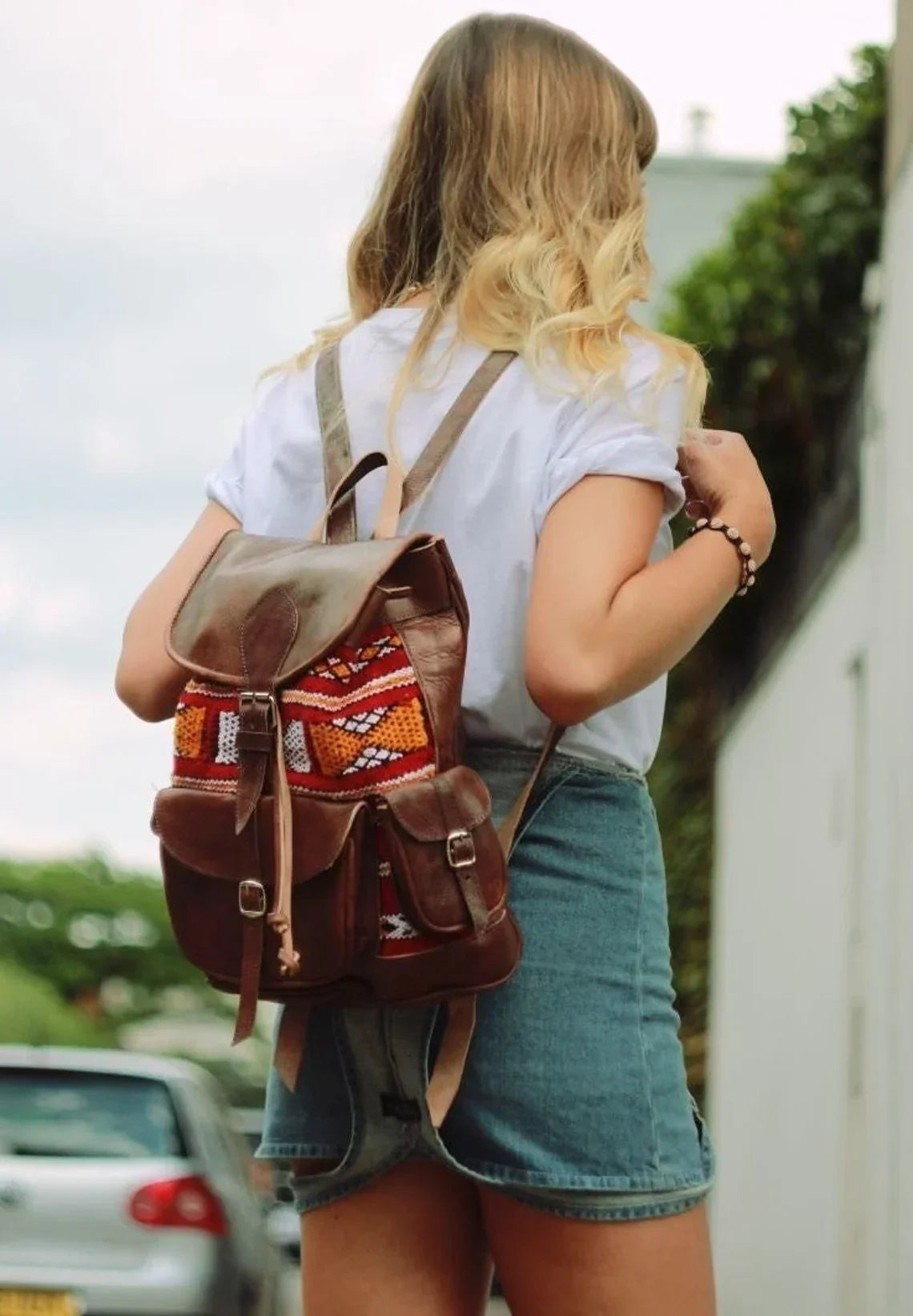 Woman wearing a brown leather backpack with colorful Berber pattern embroidery