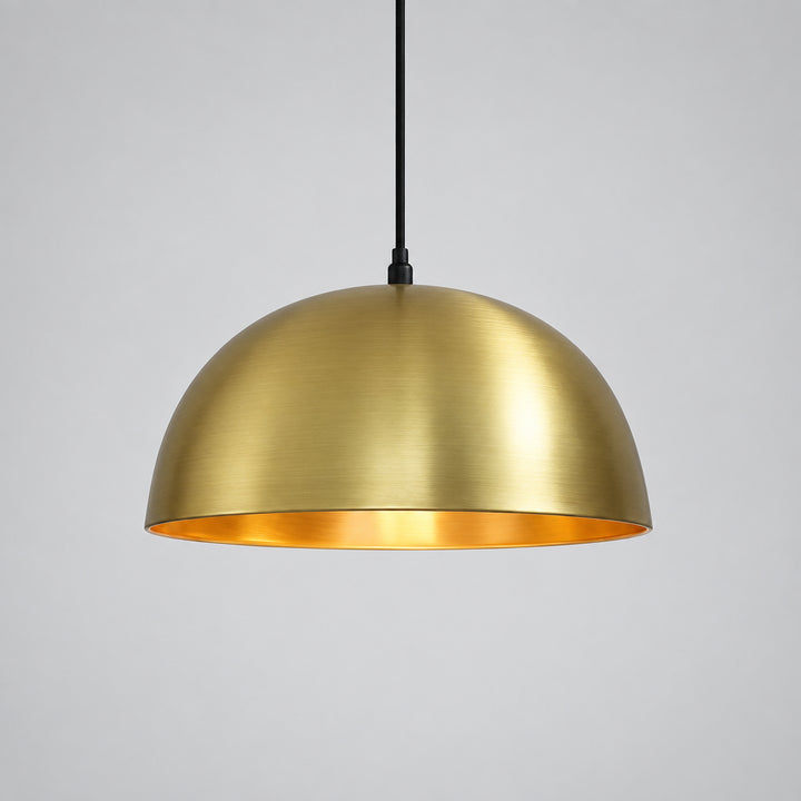 A gold-colored pendant light hangs from the ceiling against a beige wall.