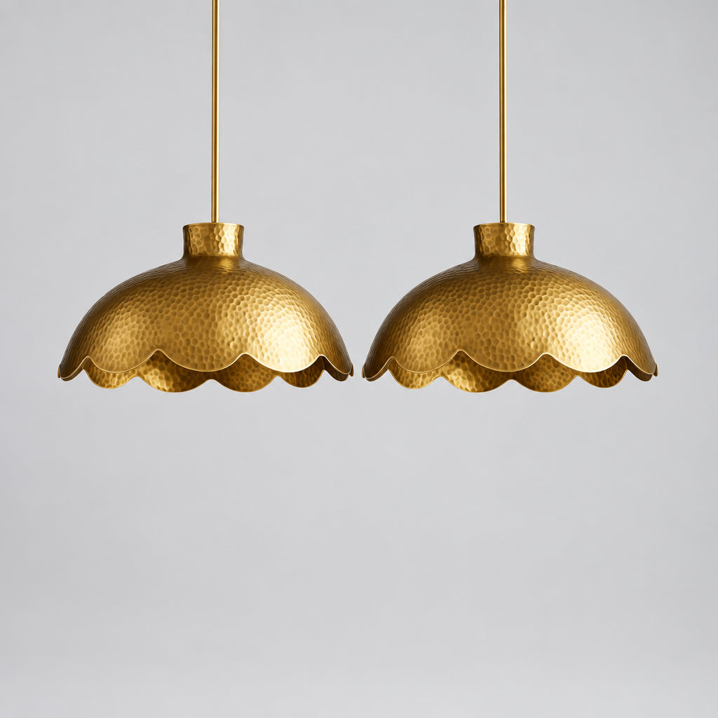 two gold-colored scalloped pendant lights hanging from the ceiling in a kitchen setting.
