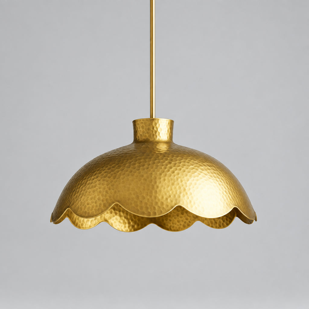 A gold-colored pendant light fixture with a scalloped edge hangs from a hook against a beige background.